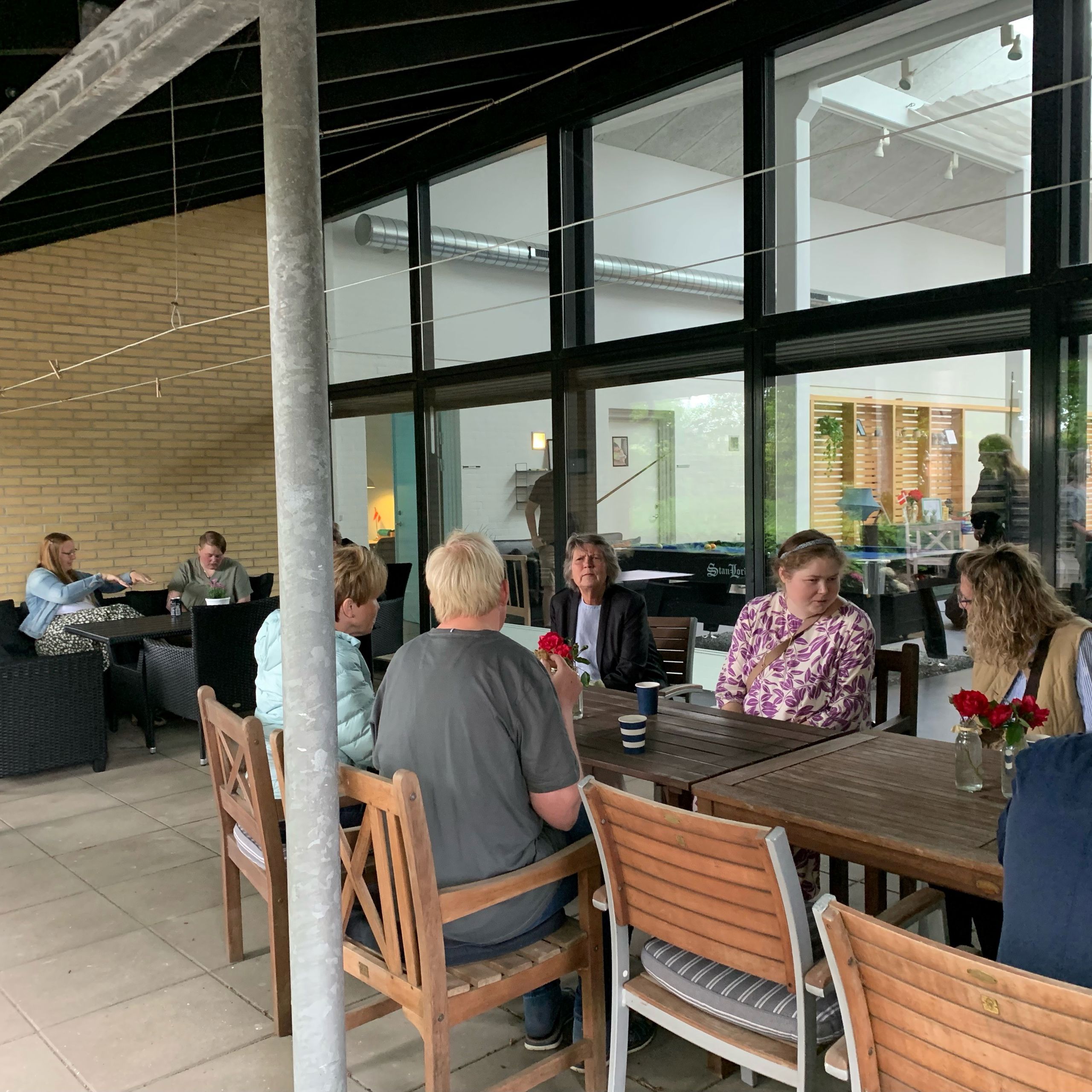 Der sidder en flere borgere ved tre terrasseborde og snakker