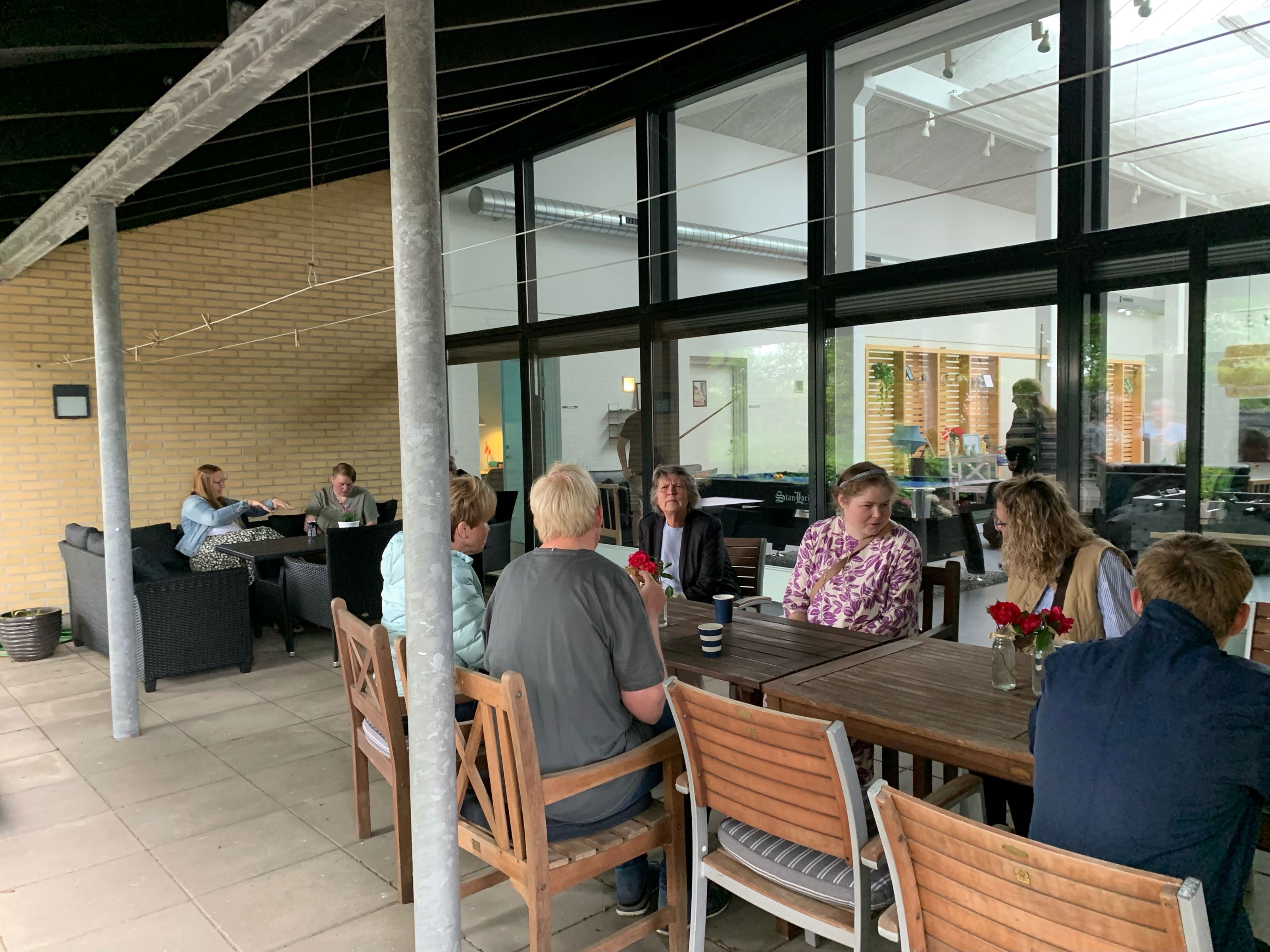 Der sidder en flere borgere ved tre terrasseborde og snakker