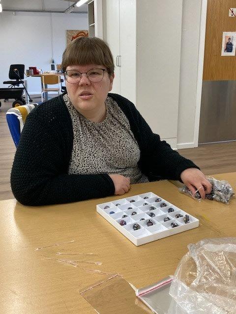 Borger sidder og pakker små metaldele i en æske hvor der er en masse små rum. Foran æsken ligger der også små lynlåsposer der kan pakkes varer i.