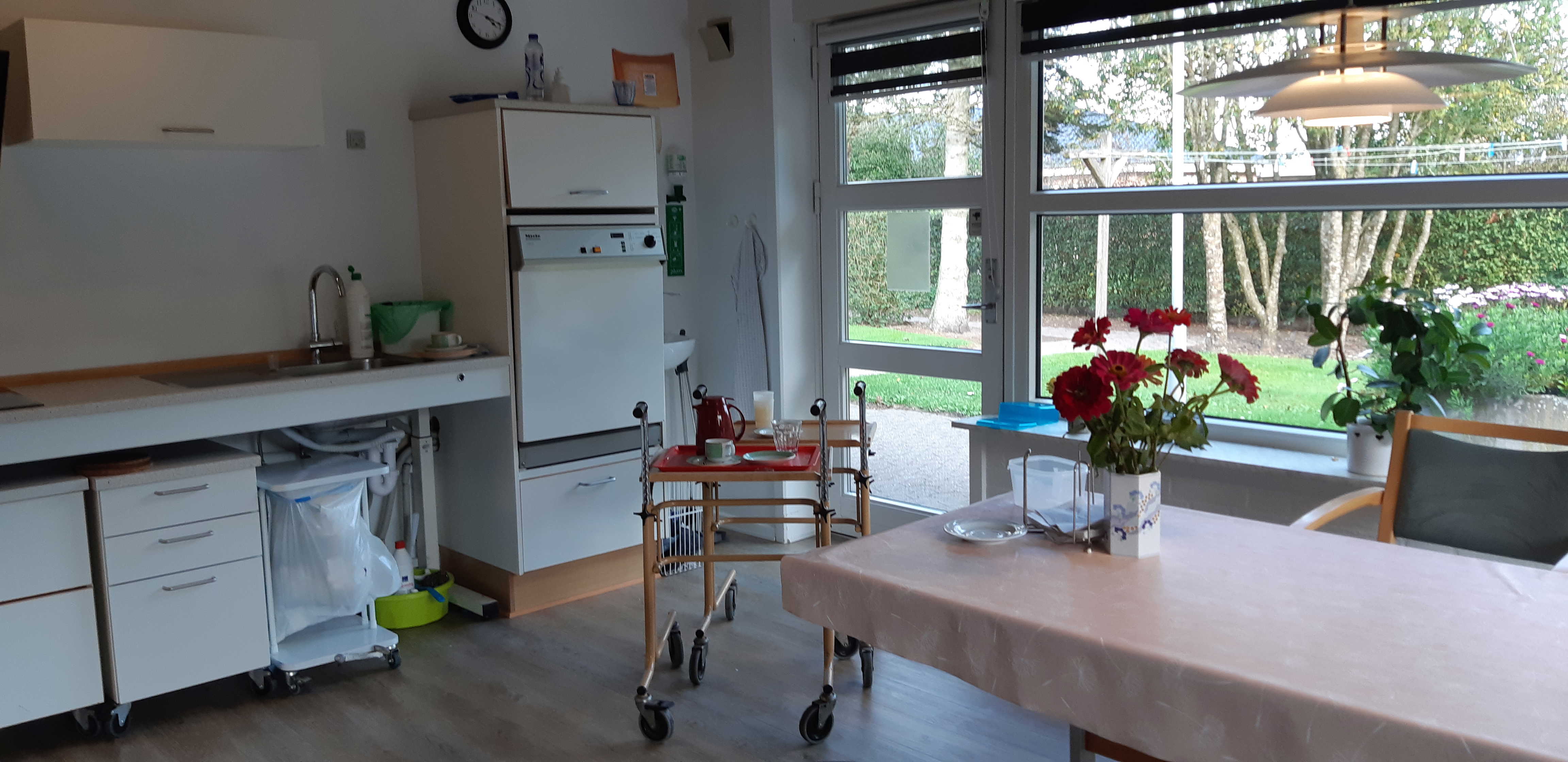 køkken med spiseplads og der er røde blomster på bordet.