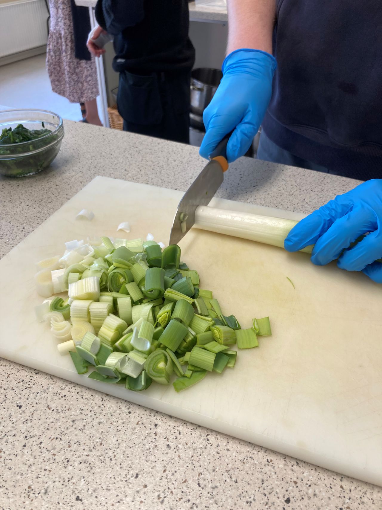 Der bliver skåret porrer ud til maden, der bliver brugt handsker.