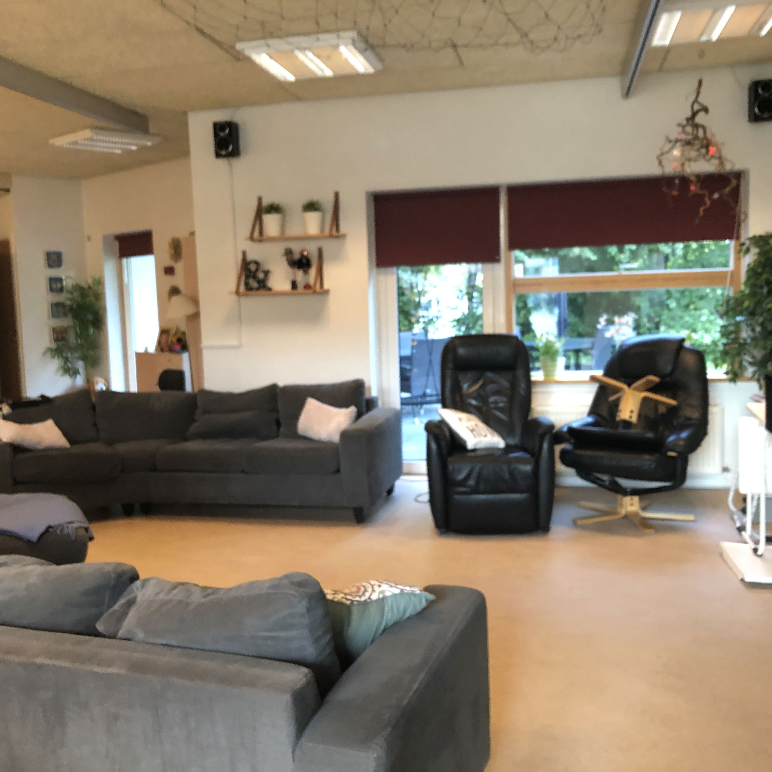 I opholdsrummet til venstre står der to sofaer overfor hinanden. Ved den ene sofa er der to læder lænestole. Gulvet er lyst laminatgulv. I enden af rummet er der et stort vindue og en terrassedør.