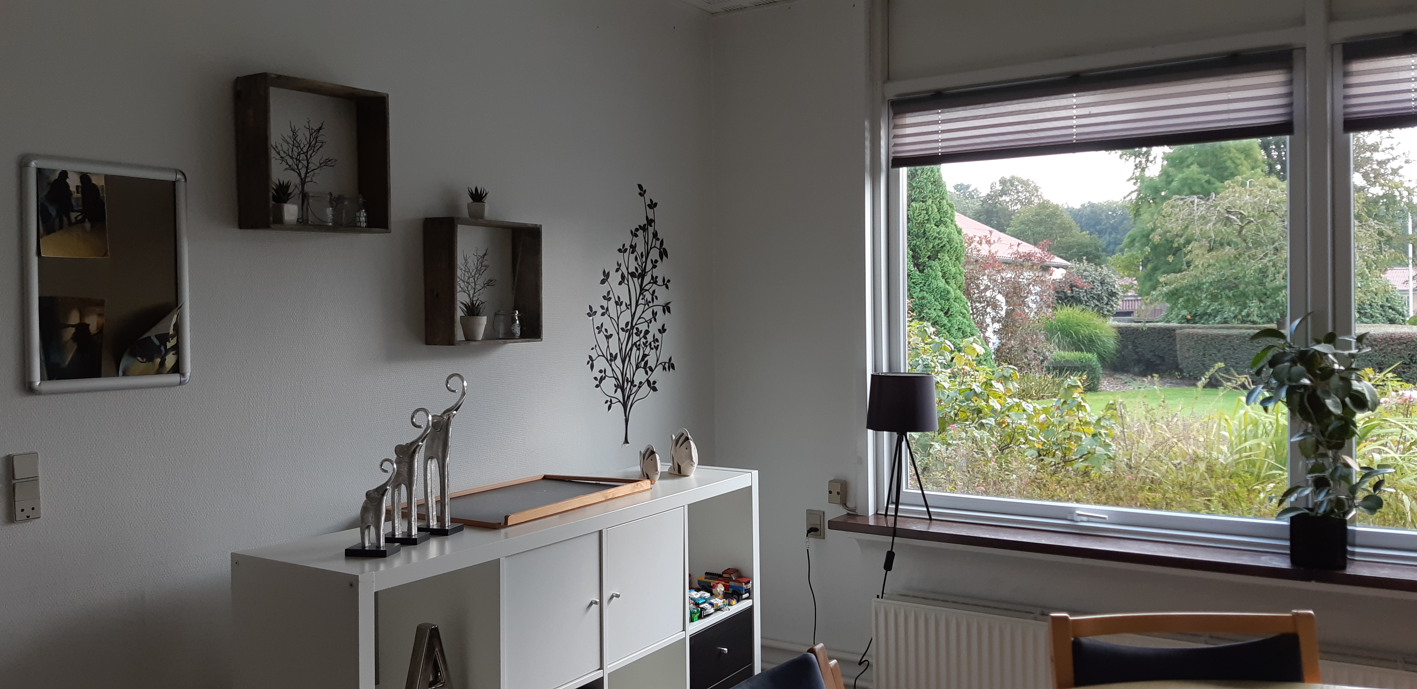 Leglighed hvor der en reol, et bord med stole og billeder på væggen 