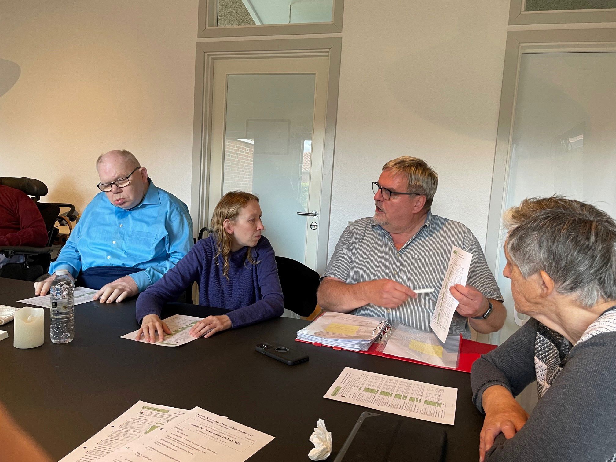 Medarbejder fra Boligkontoret sidder og gennemgår budgettet med personerne omkring bordet.