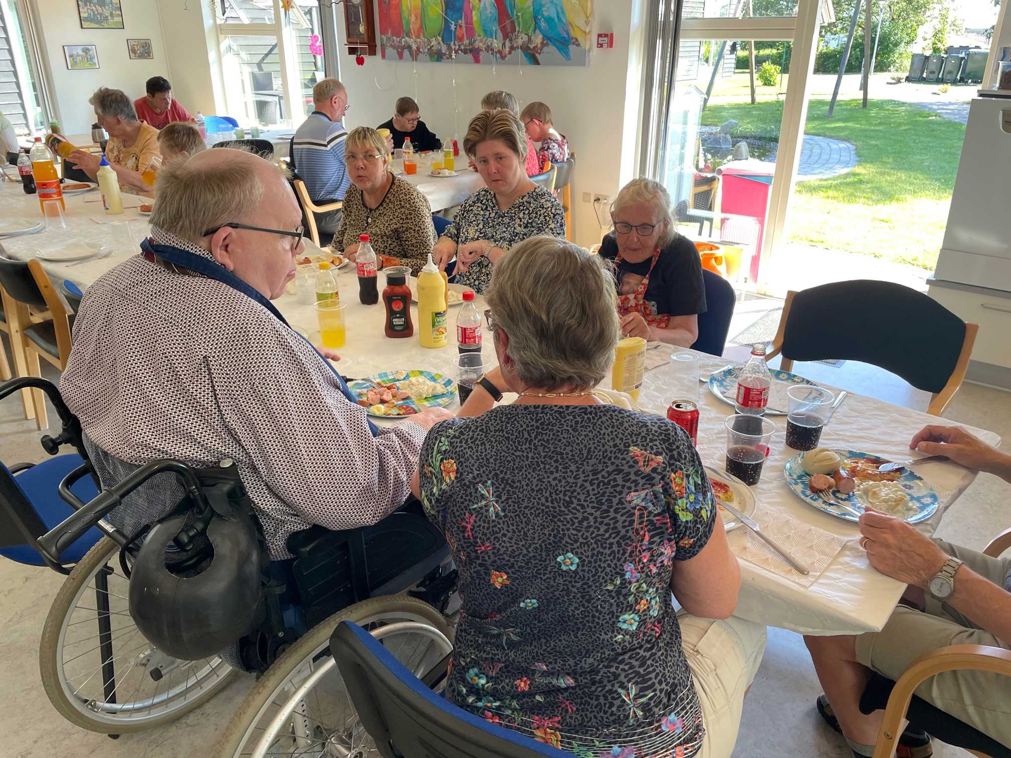 Man ser borgerne hygger sig med maden, døren ud til gårdhaven er åben og det er rigtig godt vejr.