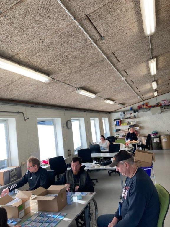 Tre borgere sidder og pakker kort, de skal alle samles og sender derefter.