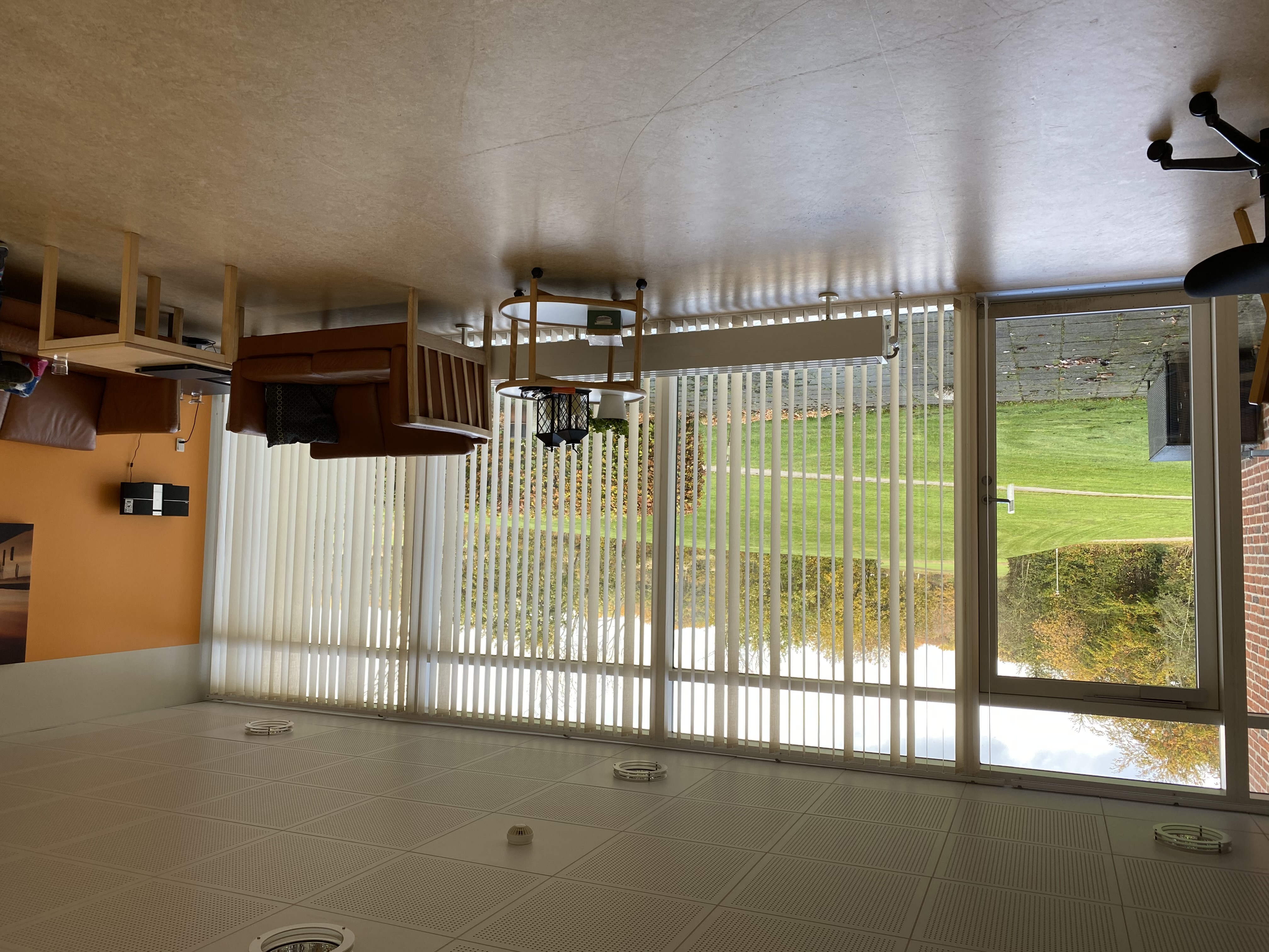 Opholdsstuen på Æblevej 1 er der to brune læder sofaer og et lille firkantet bord. Den ene væg i  stuen er malet orange. Gulvet er lysebrunt. 