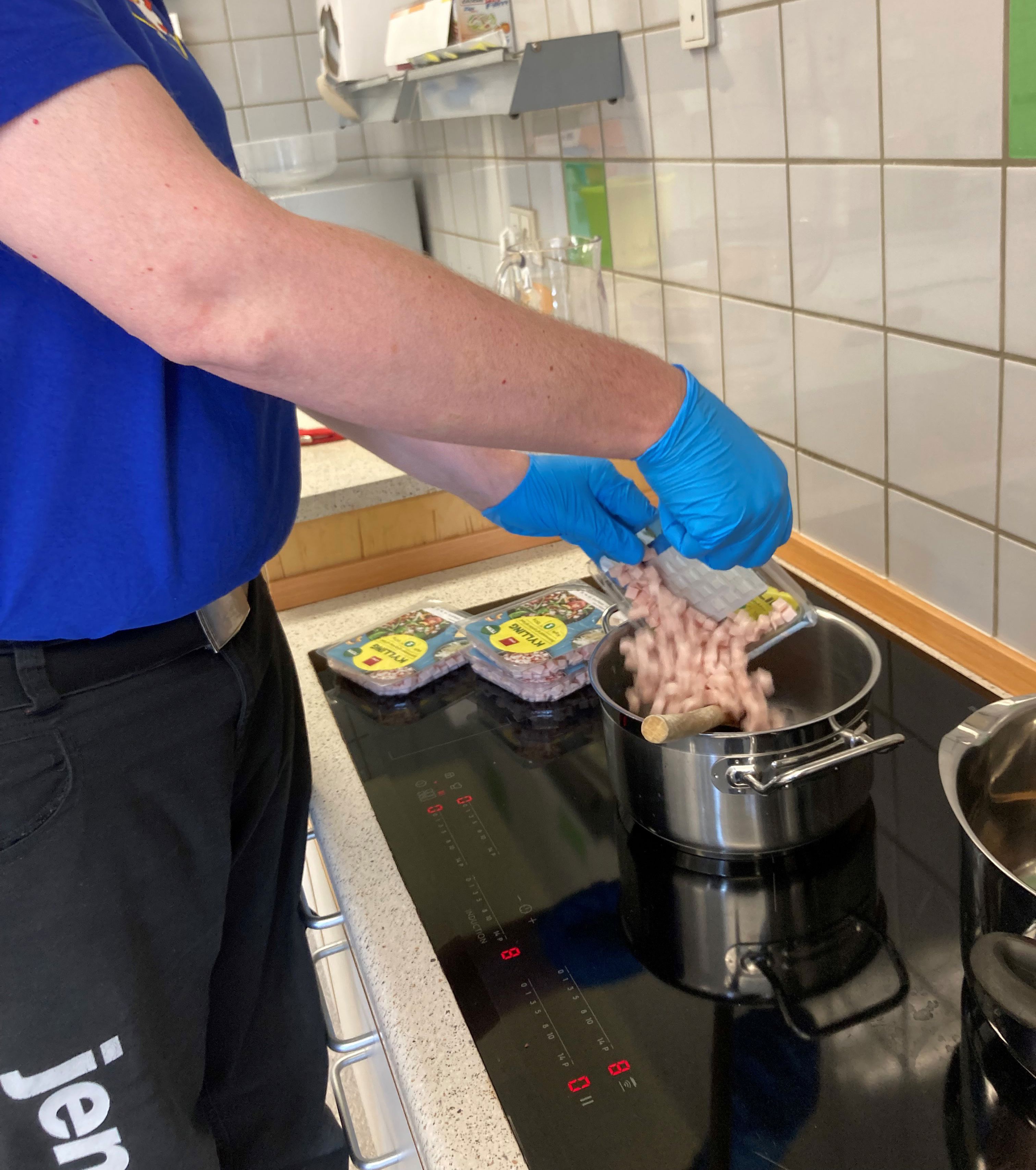 En borger er ved at åben nogle pakker med kød og putte dem i en gryde.