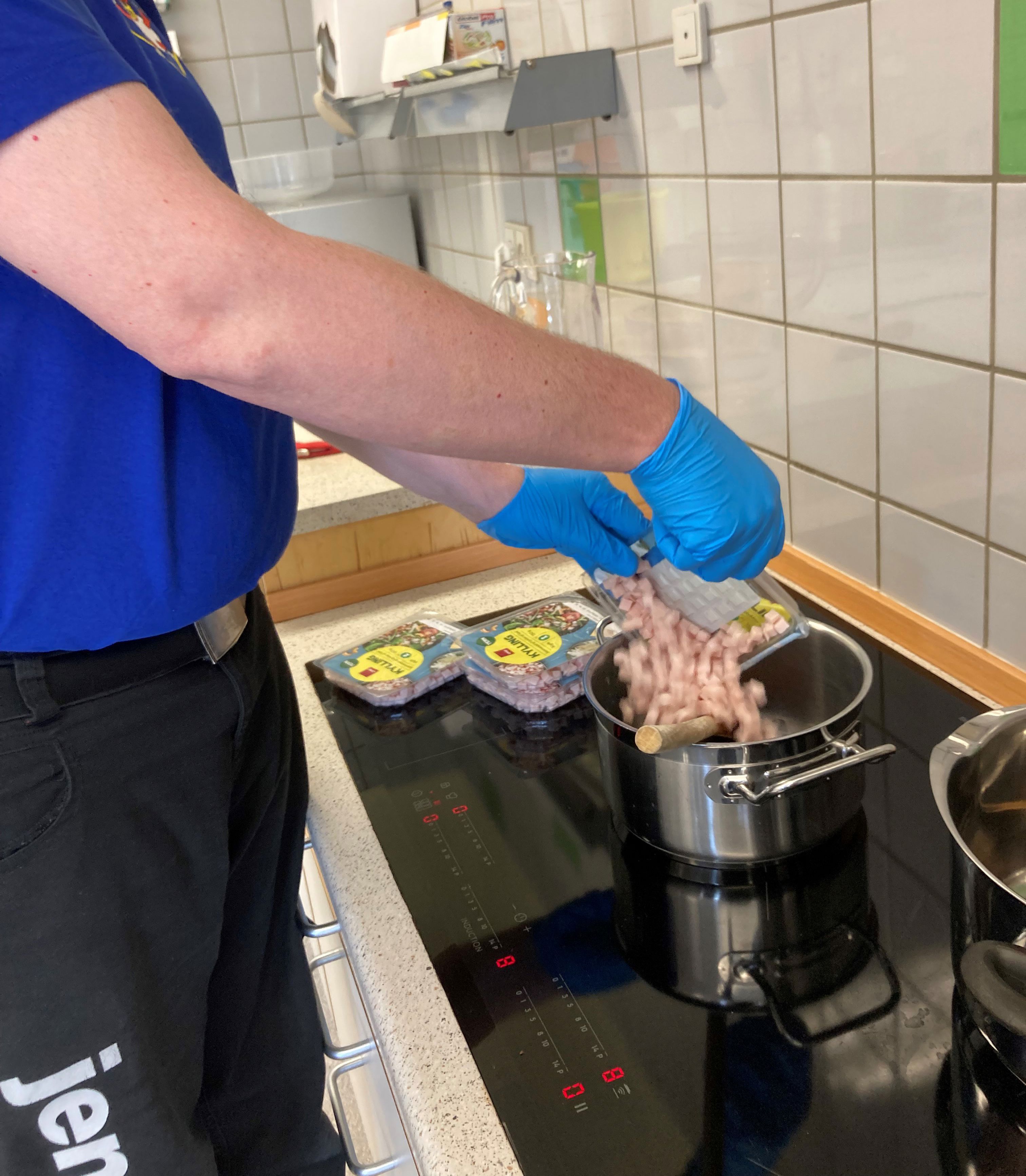 En borger er ved at åben nogle pakker med kød og putte dem i en gryde.