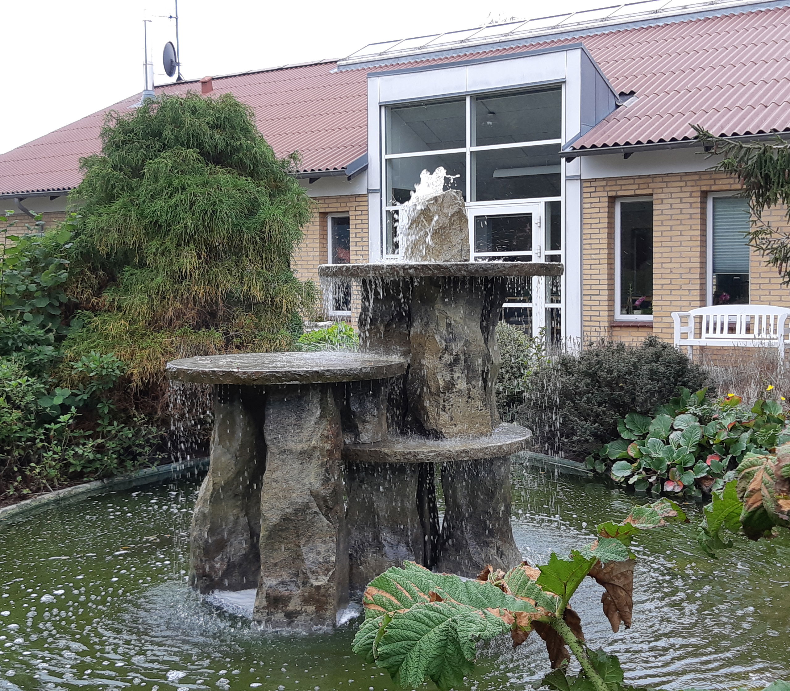 Springvandet ude i haven hvor bygningen af Solengården er i baggrunden.