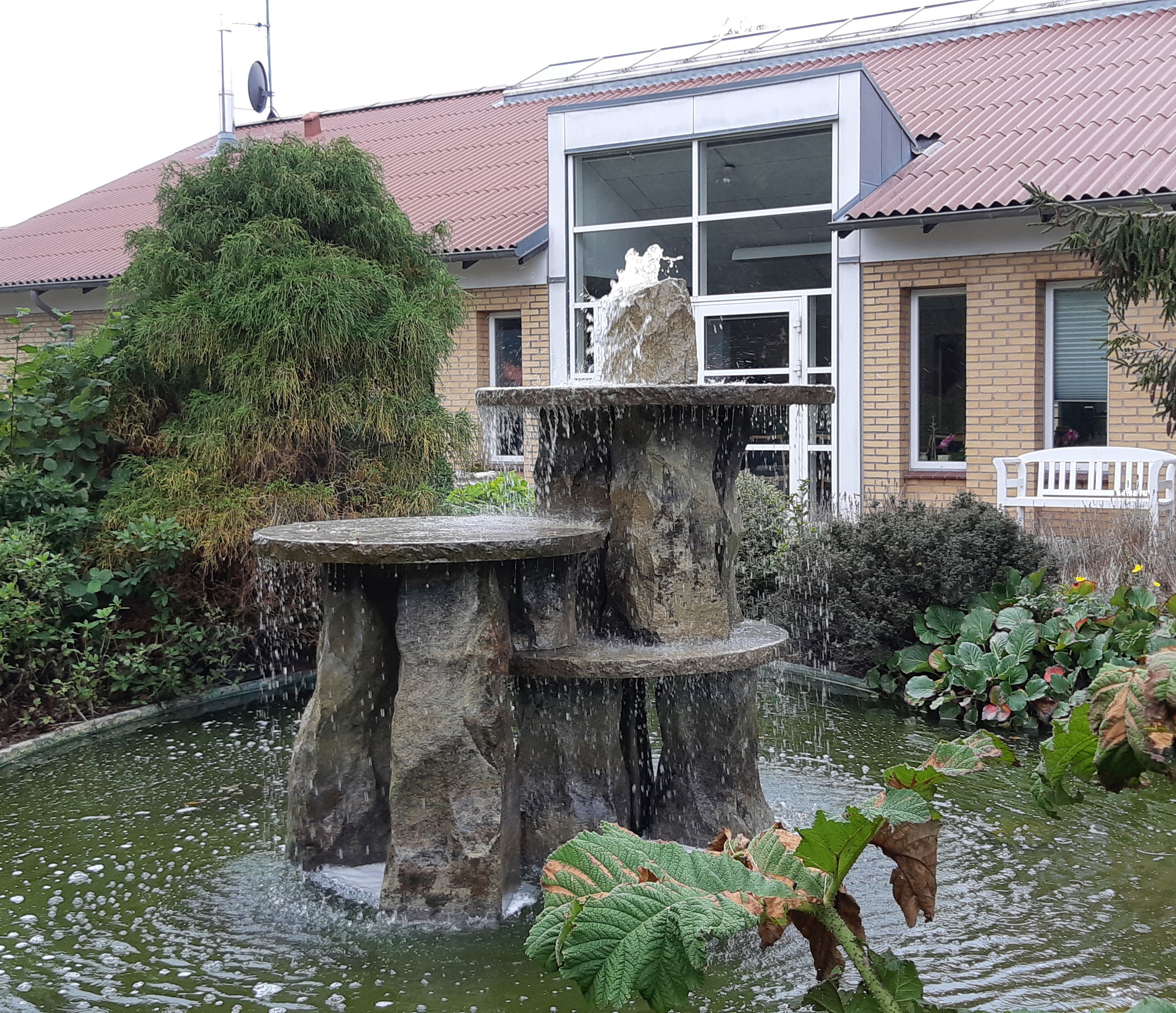 Springvandet ude i haven hvor bygningen af Solengården er i baggrunden.