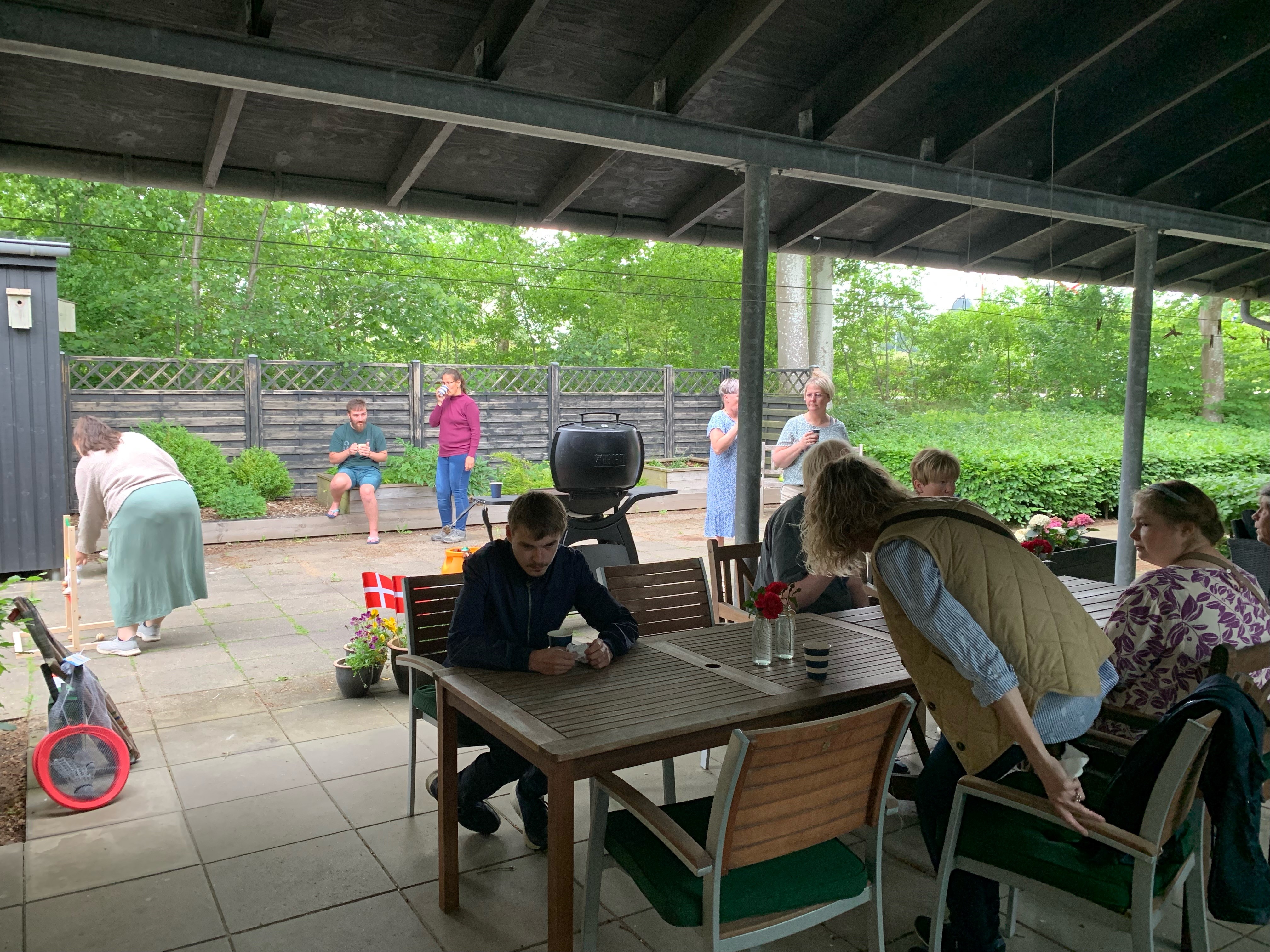 Borgere sidder og snakker, mens der i baggrunden spilles stigegolf