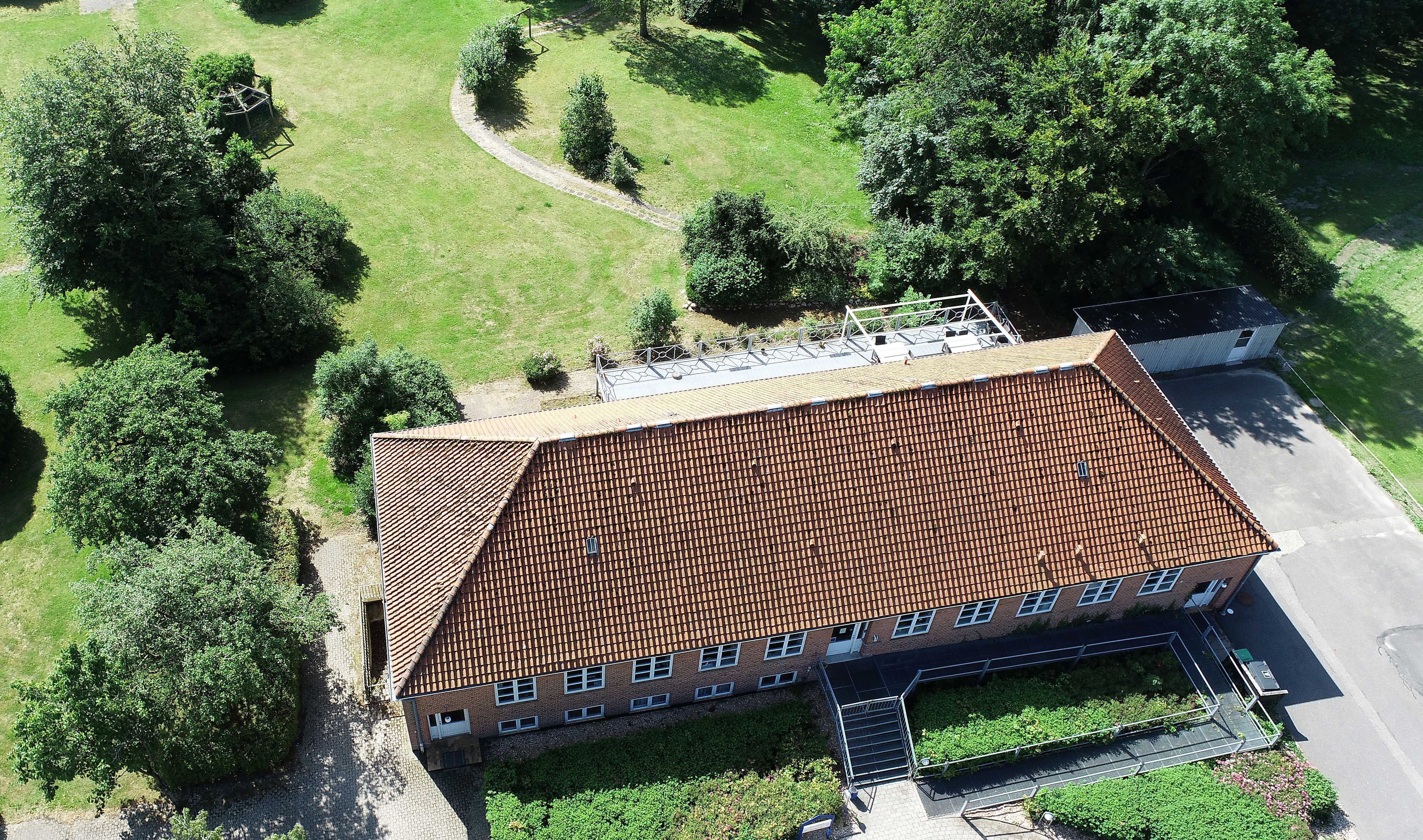 Luftfoto af bygning på løgumgårde, det er en bygning med røde mursten hvis vinduer og et rødt tag.