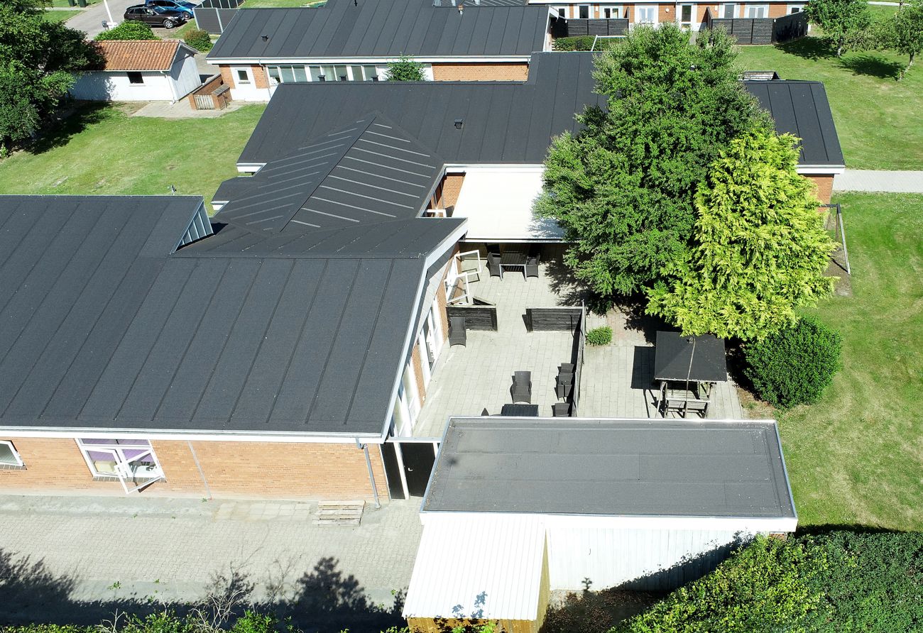 Luftfoto af bygning med gule mursten hvide vinduer og sort tag