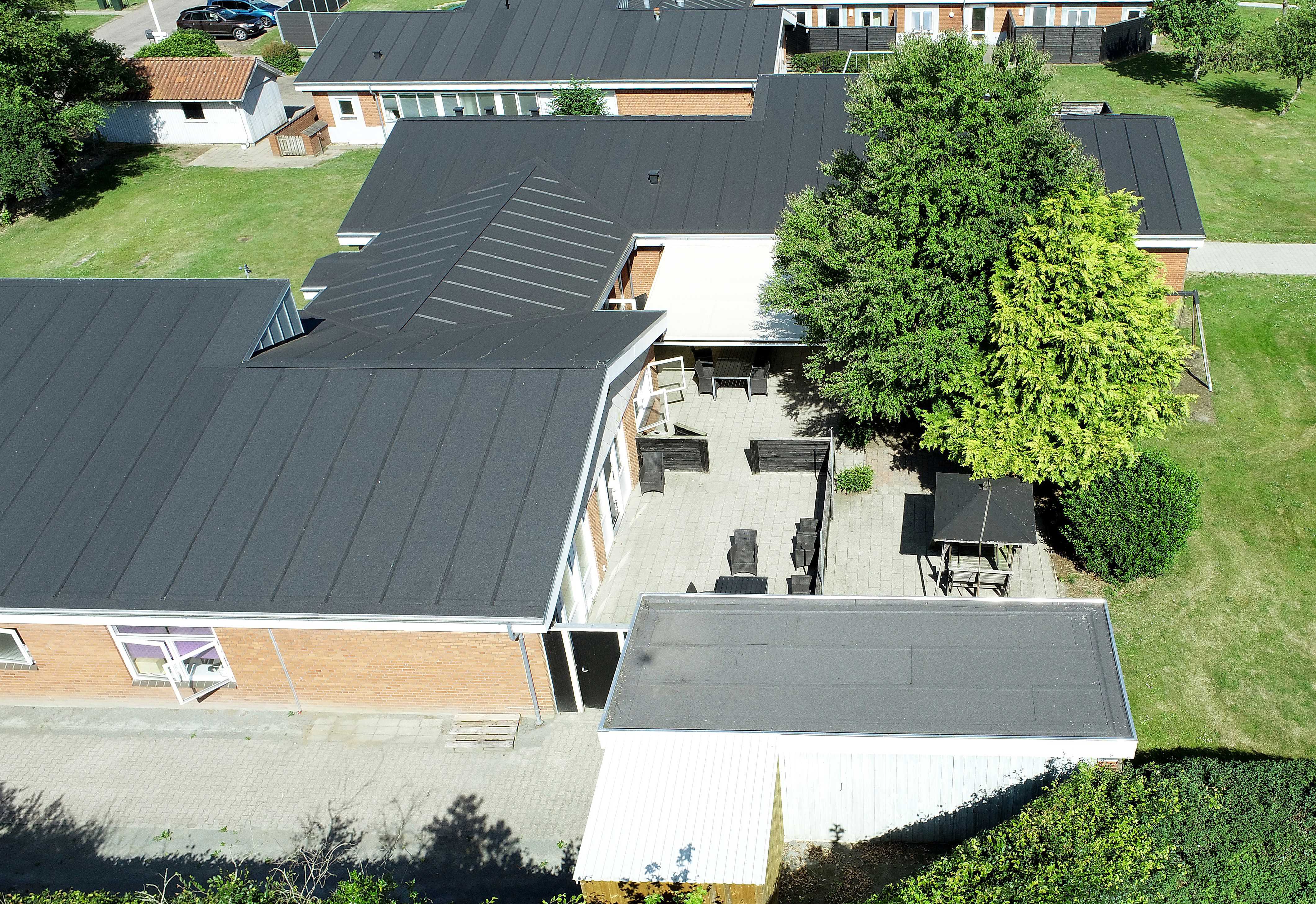 Luftfoto af bygning med gule mursten hvide vinduer og sort tag