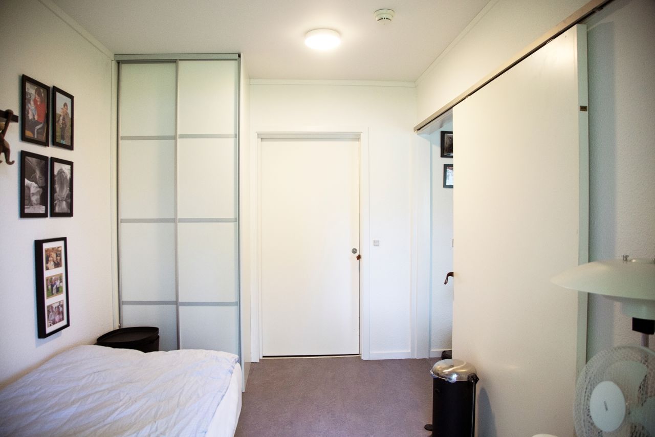 Soveværelse hvide vægge en seng med hvidt sengetøj på væggen er der billeder af mennesker