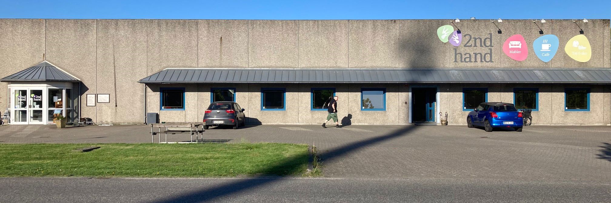 Oversige over 2Nd Hand butikken udefra man kan se skiltene i forskellige farver med tekst på
