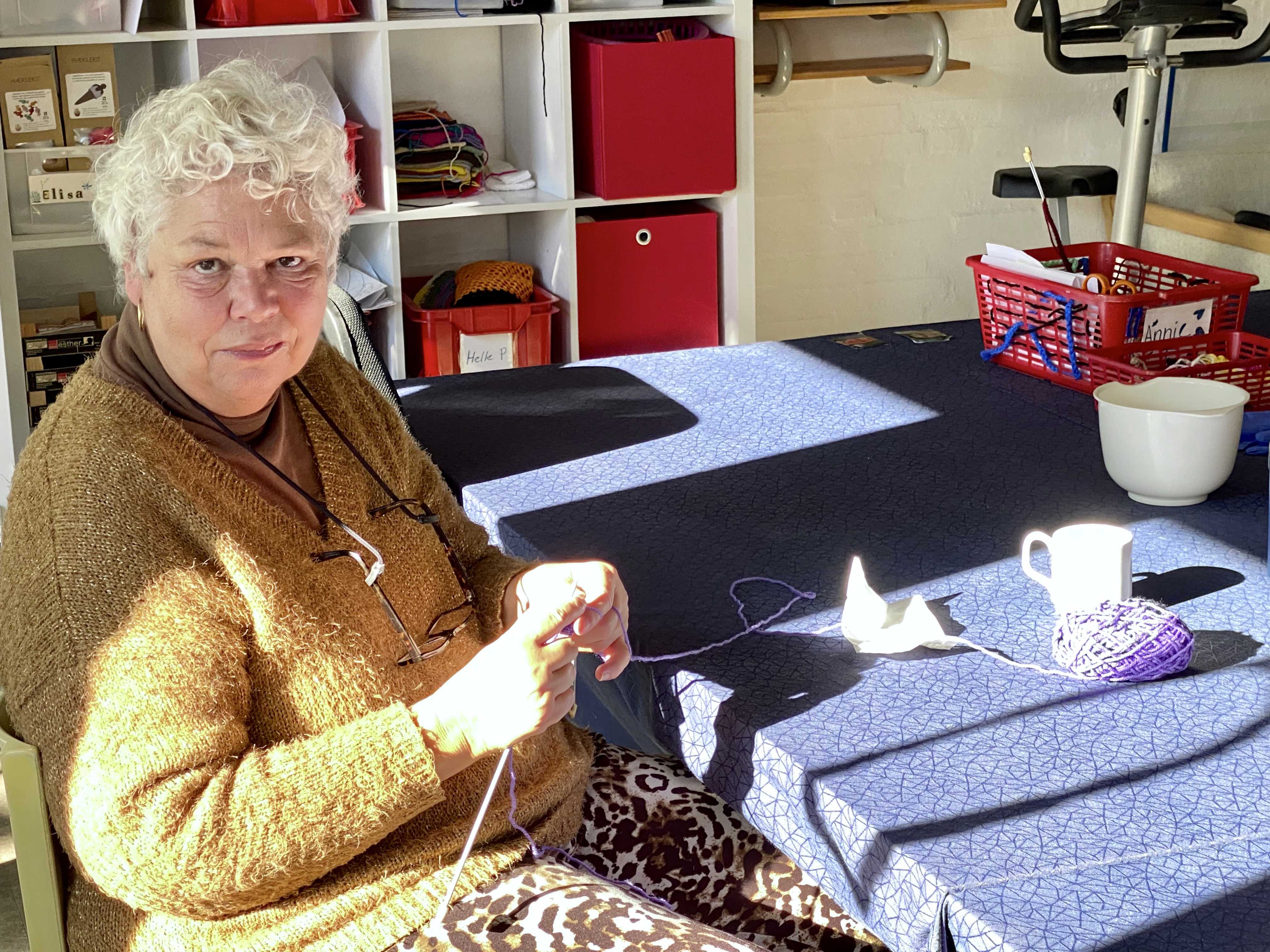 En borger sidder ved et bord og strikker
